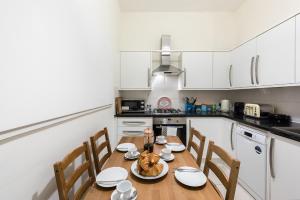 伦敦Heart of Ealing Apartment with Garden的厨房配有木桌、椅子和桌子
