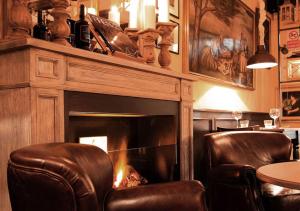 卢卡The Tuscanian Hotel的壁炉,配有两把椅子和一张桌子