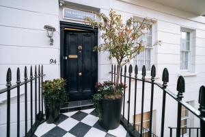 伦敦The Warwick By Aura Collection的白色房子上一扇黑色的门,上面有植物