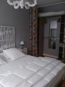 勒特雷波尔L' entre mer et falaise的卧室内的一张白色大床,配有吊灯
