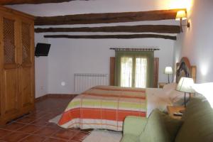 Las Cuevas de CañartCasa Rural La Buhardilla的一间卧室配有一张床和一张沙发