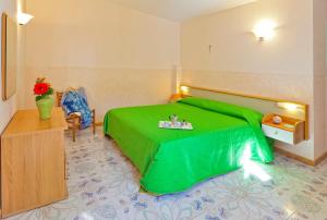 伊斯基亚假日公园大酒店的一间卧室配有一张绿色的床,上面有桌子