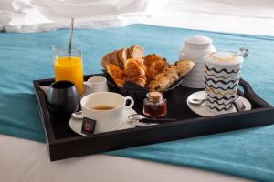 波尔蒂乔Hotel le Jardin d'Emile的床上的早餐盘,包括咖啡和糕点