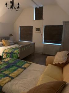 米尔登霍尔苹果树住宿加早餐旅馆的一间卧室设有两张床、一张沙发和两个窗户。