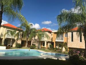 蓬塔卡纳Punta Cana Apartment and scooter for free的棕榈树建筑前的游泳池