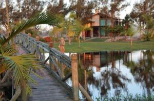 Balneário GaivotasCasa condomínio lagoa cortada的一座木桥,在池塘上,背靠房子