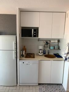 勒格罗-迪鲁瓦Studio climatisé à 5 minutes de la plage的厨房配有白色橱柜和白色冰箱。