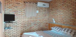 卡诺格布拉达Mar à vista的一间卧室设有砖墙、一张床和电视