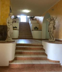OttanaHOTEL FUNTANA E DONNE的两座建筑物楼梯上的雕像