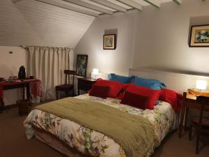 布兰维尔苏米尔lesroses1680的一间卧室配有一张带红色和蓝色枕头的床
