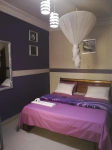 达喀尔卡兰奎斯公寓式酒店的一间卧室配有一张带紫色床单和镜子的床
