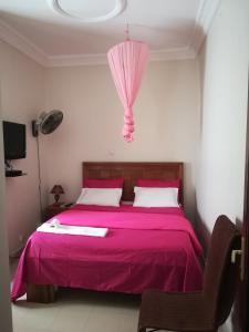 达喀尔卡兰奎斯公寓式酒店的一间卧室配有粉红色的床和粉红色的雨伞