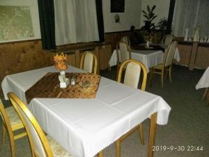 KytlicePension Helene s mini pivovarem的一间用餐室,配有两把桌子和椅子以及白色的桌布