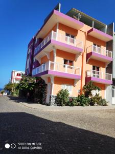 蓬塔杜索尔Casa Celeste的街道上一座带粉红色和紫色阳台的建筑