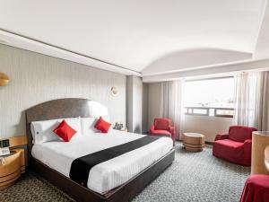 墨西哥城Capital O Andrade, Mexico City的酒店客房带大床和红色椅子