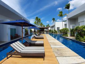 卡塔海滩BLU PINE Villa & Pool Access - SHA Plus的度假酒店的游泳池配有躺椅和遮阳伞