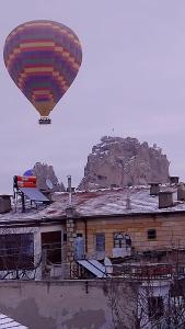 乌奇希萨尔Capiedra Hotel的热气球在大楼上空飞行