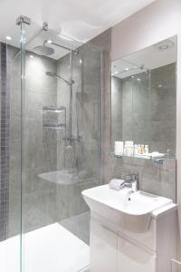 剑桥Citystay - Hinton House的一间带水槽和玻璃淋浴的浴室