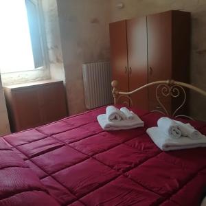 洛科罗通多Trulli Manuela 2的一间卧室配有红色的床和毛巾