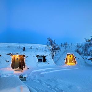 KokelvModern turf house的雪上带灯的雪盖房子