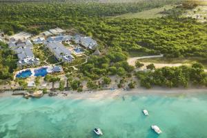 巴亚希贝Hilton La Romana All- Inclusive Adult Resort & Spa Punta Cana的海滩上乘船的度假村空中景色
