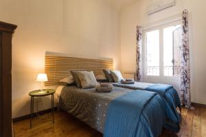 巴勒莫Terrazza Politeama的一间卧室配有一张带蓝色毯子的床和窗户。