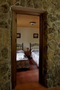 纳瓦伦加casa rio alberche y el cortijo de gredos的一间设有两张床和石墙的房间
