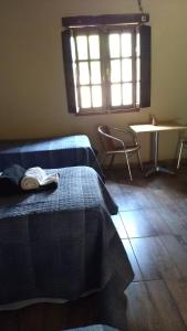 FamatinaFinca Las Pircas Casa de Adobe的一间卧室设有两张床、一张桌子和一个窗口