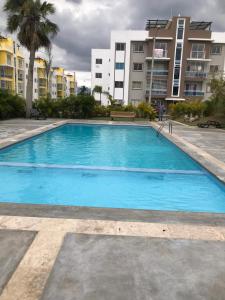 圣地亚哥洛斯卡巴moderno apto frente a la piscina的一个大型蓝色游泳池,其建筑背景为: