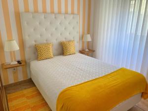 纳扎雷Duarte Houses T2 - com vista mar的卧室配有一张白色大床和黄色床单