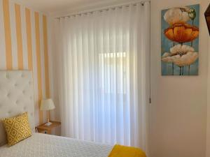 纳扎雷Duarte Houses T2 - com vista mar的一间卧室配有床和白色窗帘的窗户