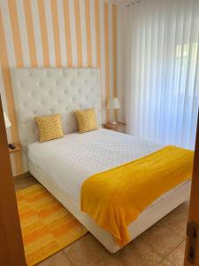 纳扎雷Duarte Houses T2 - com vista mar的卧室配有白色床和黄色毯子