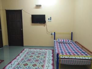 巴生Homestay Teratak Umi Klang的卧室配有一张床,墙上配有电视。