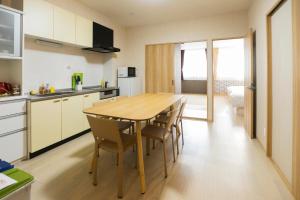 大阪guest house Sora的厨房以及带木桌和椅子的用餐室。
