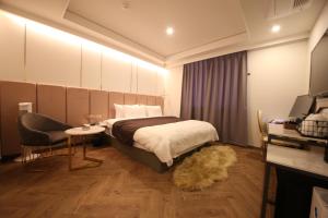 釜山Den Basta Hotel的卧室配有1张床、1张桌子和1把椅子