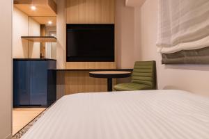 福冈Hotel Vista Fukuoka Nakasu-Kawabata的一间卧室配有一张床、一台电视和一把椅子