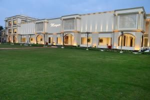 SītāpurMayur Hotel & Resort的一座大型建筑,前面有一个大型的绿色场地