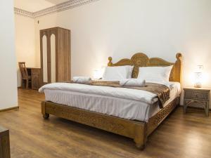 布哈拉Royal Bukhara hotel的一间卧室配有一张大床和木制床头板