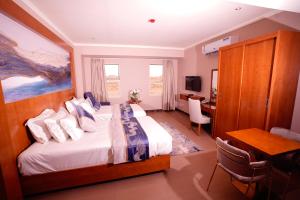 达曼Suite blue的酒店客房配有一张床、一张书桌和一张书桌。