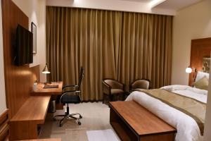 SītāpurMayur Hotel & Resort的配有一张床和一张书桌的酒店客房