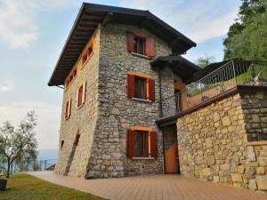 蒙泰伊索拉IseoLakeRental - La Stallina - Monte Isola的石头房子设有红色窗户和阳台