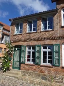 普劳西Altes Fischerhaus的砖屋,设有绿色的白色窗户