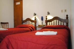 科洛尼亚-德尔萨克拉门托罗米酒店的宿舍间内的两张床,配有红色的床单和毛巾