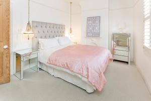 艾纯查姆Stamford Park Road by YourStays!的白色卧室配有粉红色的床和书桌