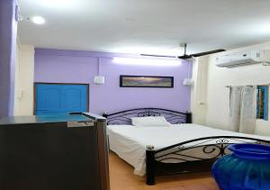 加尔各答Dden Vennell BnB -Metro Access-的一间卧室设有紫色的墙壁和一张带桌子的床