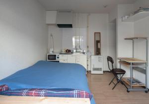 札幌Guesthouse Erimo Apartment的一间带蓝色床的卧室和一间厨房