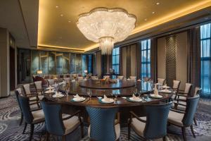 哈尔滨哈尔滨松北融创皇冠假日酒店的大型用餐室配有大桌子和椅子
