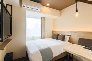 札幌Hotel Wing International Sapporo Susukino的配有一张床和一张书桌的酒店客房