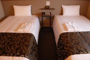 大阪PORTA INN bentencho的两张位于酒店客房的床,配有毛巾