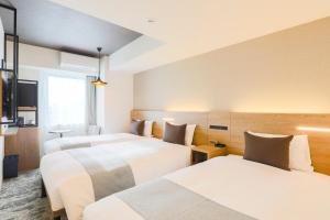 札幌Hotel Wing International Sapporo Susukino的酒店客房设有三张床和电视。